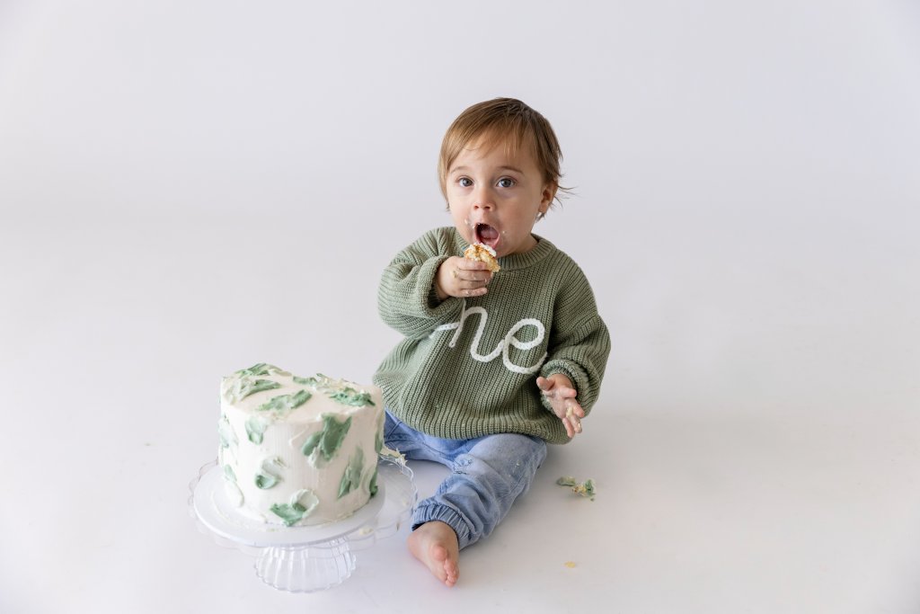 One year old boy diving into birthday cake, first birthday photography Perth