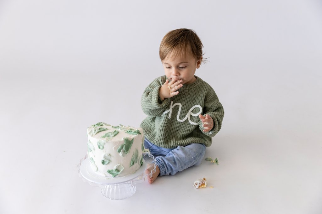 One year old boy diving into birthday cake, first birthday photography Perth
