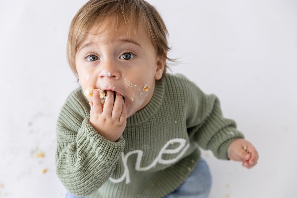 One year old boy diving into birthday cake, first birthday photography Perth