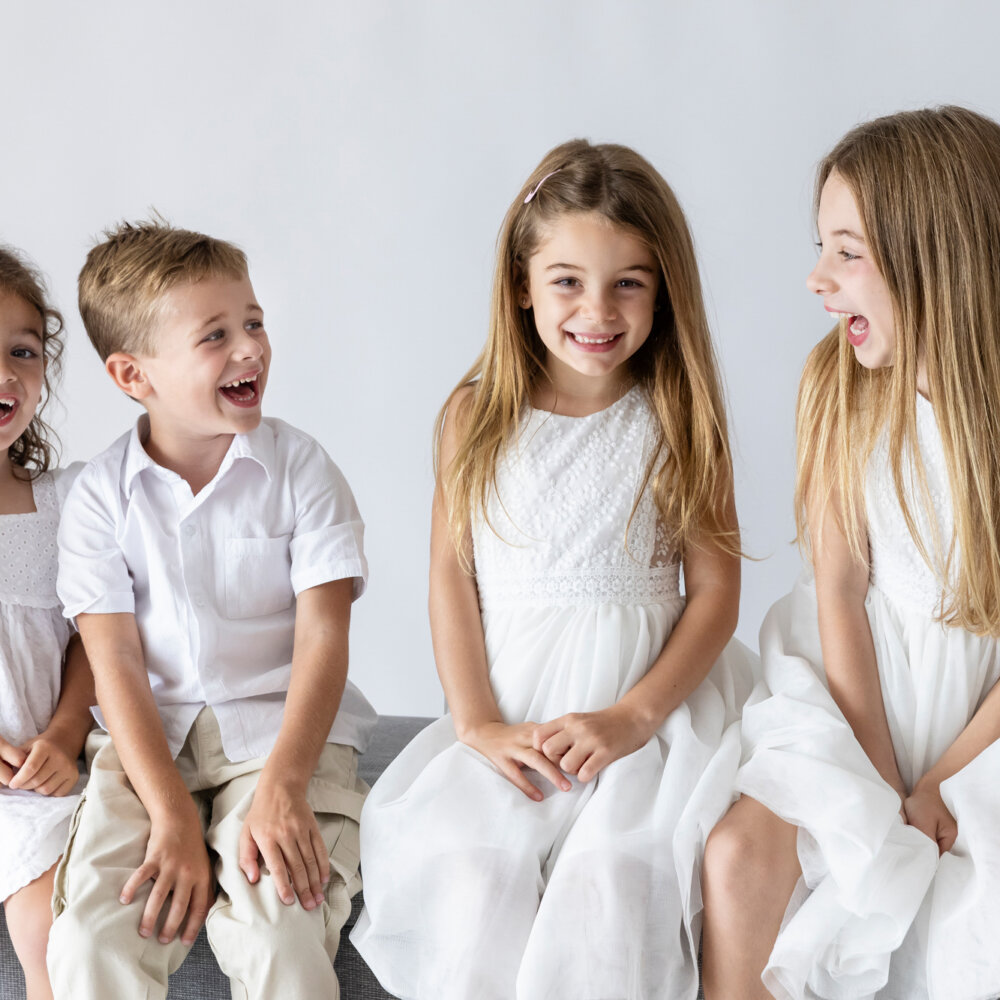four siblings laughing together in white outfits, children's photography Perth