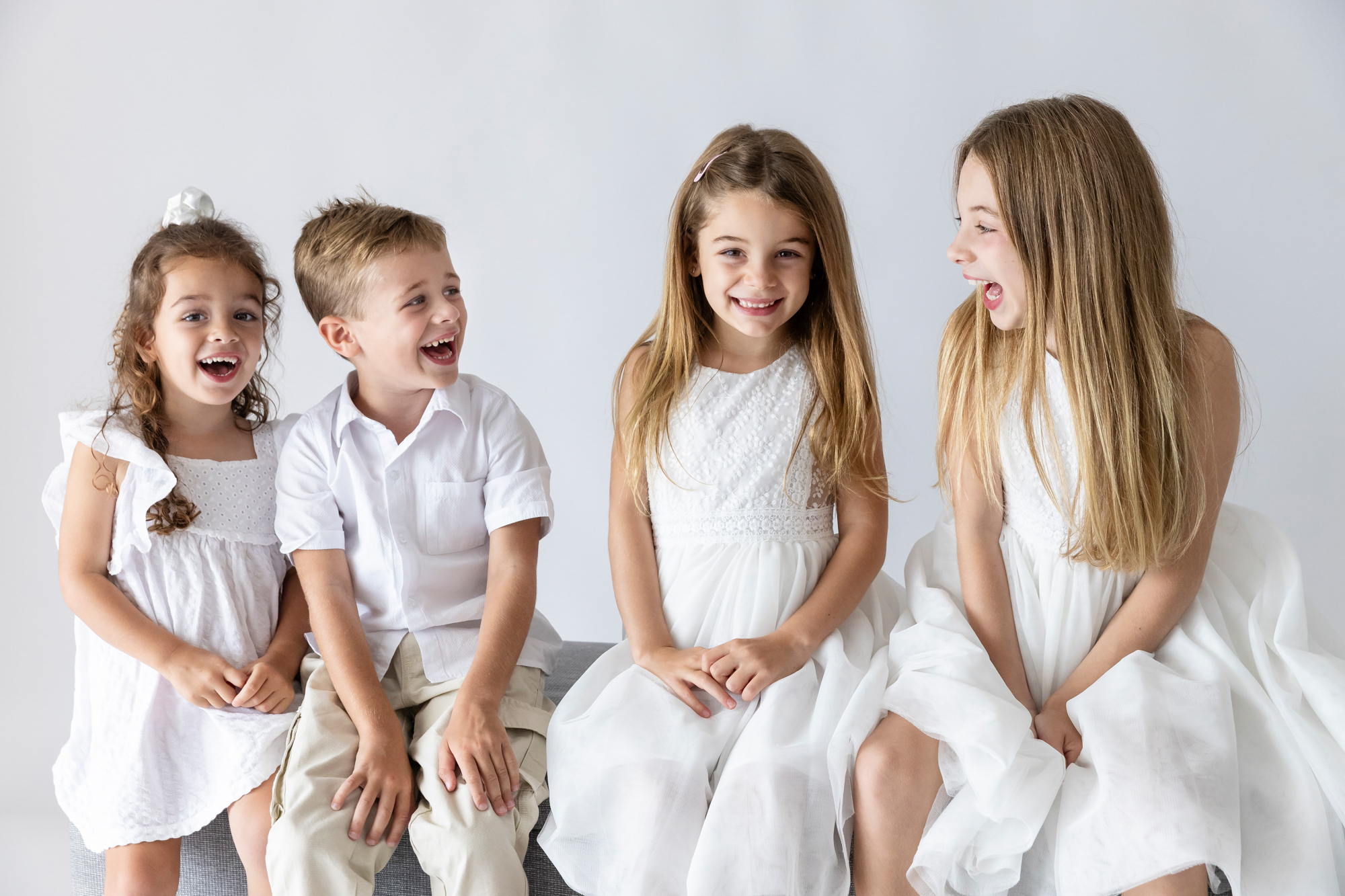 four siblings laughing together in white outfits, children's photography Perth