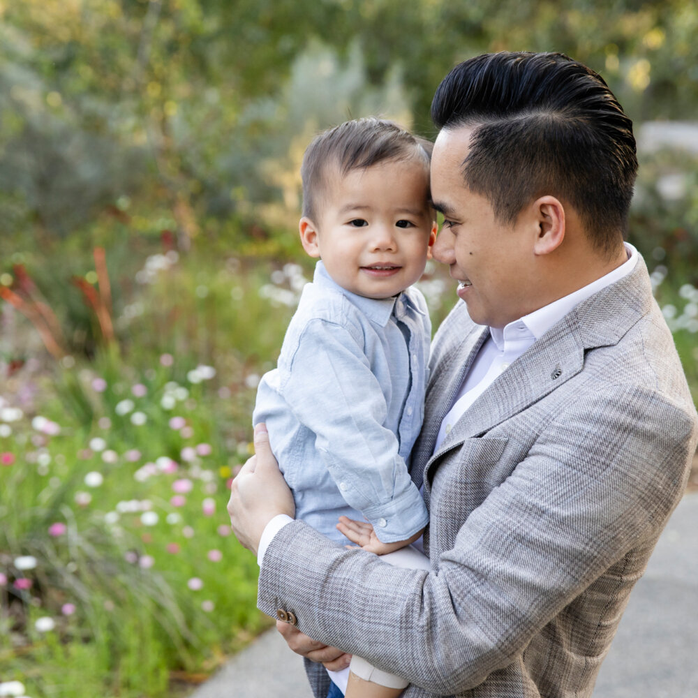 dad holding toddler son in garden among wildflowers, family photos Perth