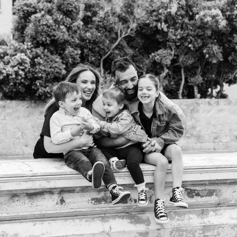 family of five laughing together on stone steps in black and white, family photography Perth