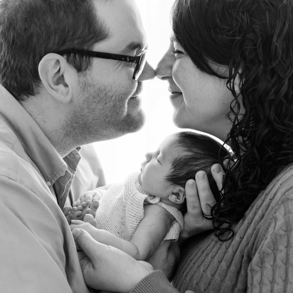 mum and dad touching noses over sleeping newborn baby in black and white, newborn photography Perth