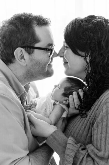 mum and dad touching noses over sleeping newborn baby in black and white, newborn photography Perth