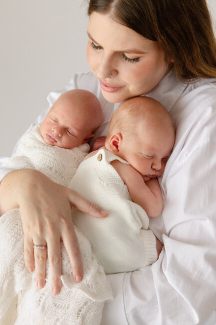 mum cradling newborn twins in white, twin newborn photography Perth