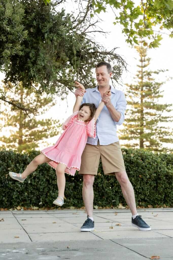 Dad dancing and spinning his daughter around laughing during a fun outdoor family photography session in Perth.
