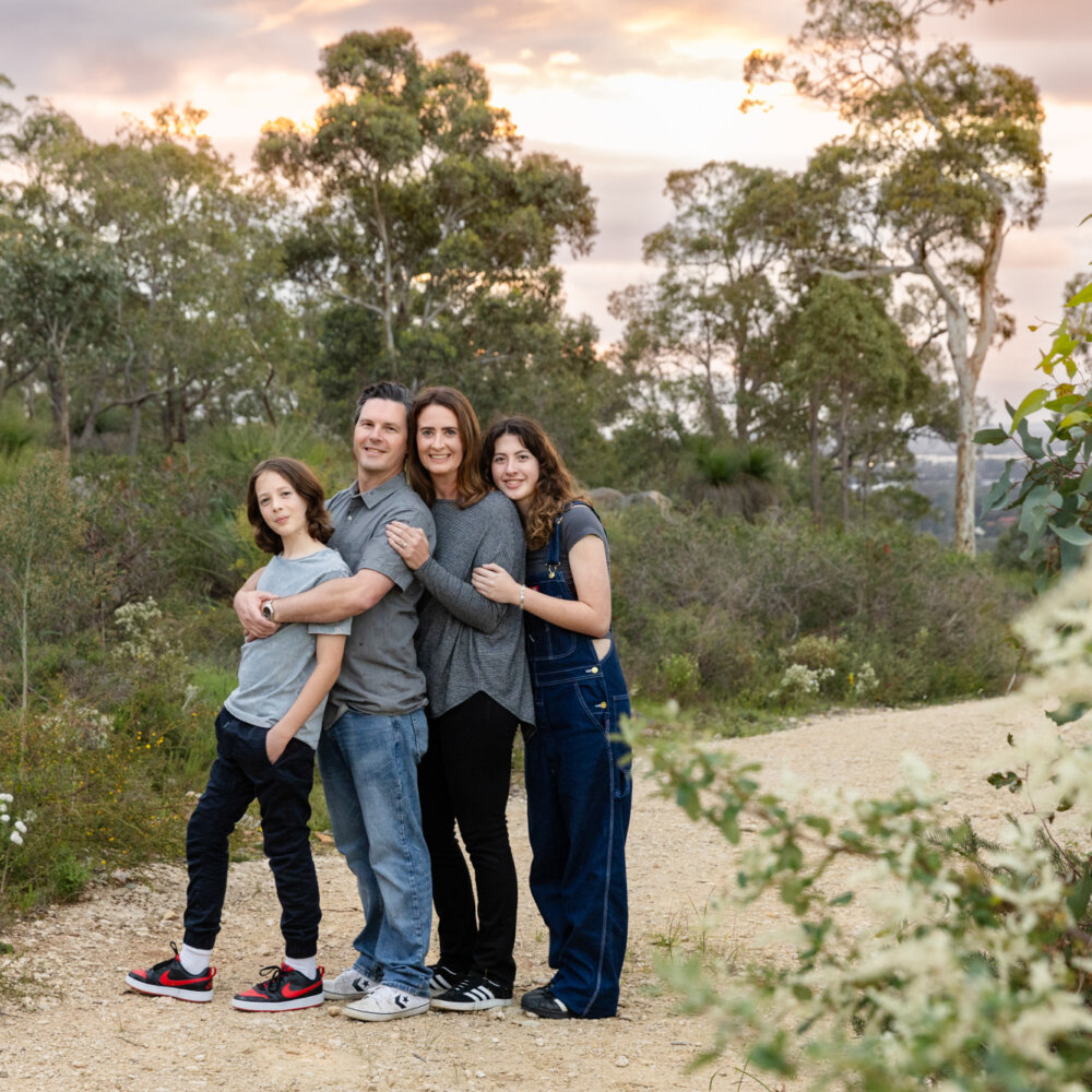 family of four hugging on bushland trail at sunset, outdoor family photography Perth
