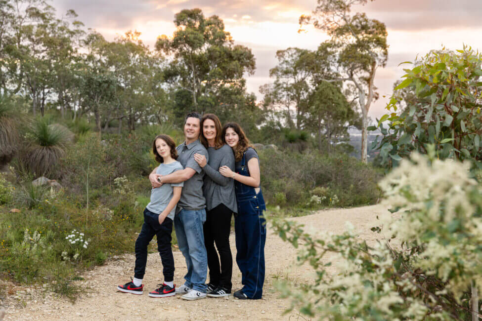 family of four hugging on bushland trail at sunset, outdoor family photography Perth