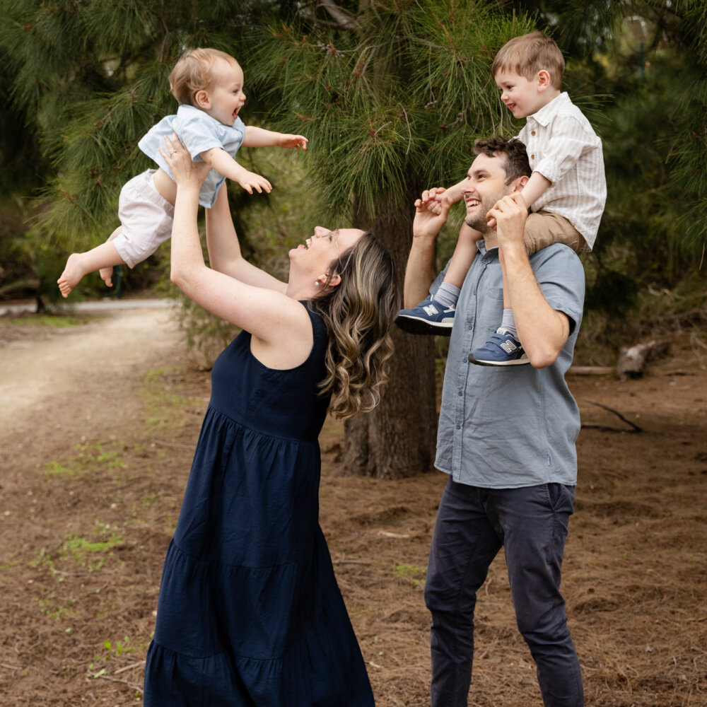 mum and dad lifting two young boys in the air laughing outdoors, family photos Perth