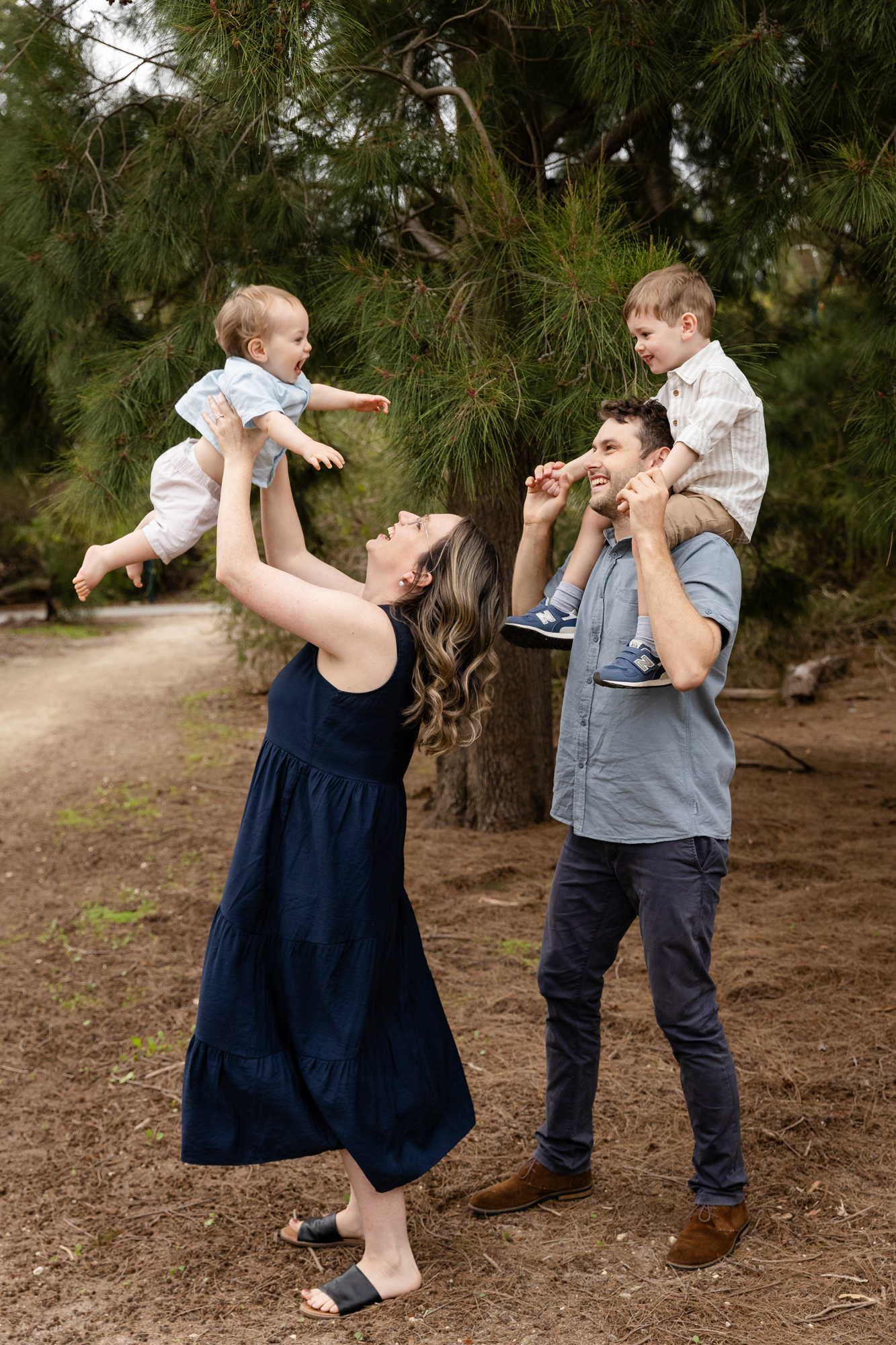 mum and dad lifting two young boys in the air laughing outdoors, family photos Perth