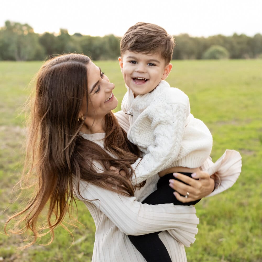 family photography Perth-mum holding laughing toddler boy in open field at golden hour