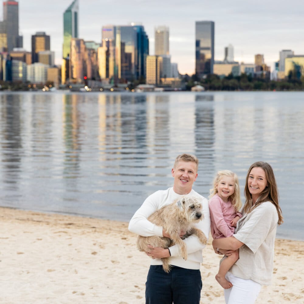 family photography Perth-family of three with dog on Perth riverfront with city skyline at sunset