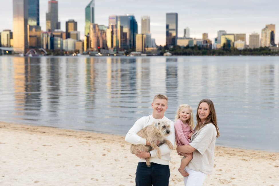 family photography Perth-family of three with dog on Perth riverfront with city skyline at sunset
