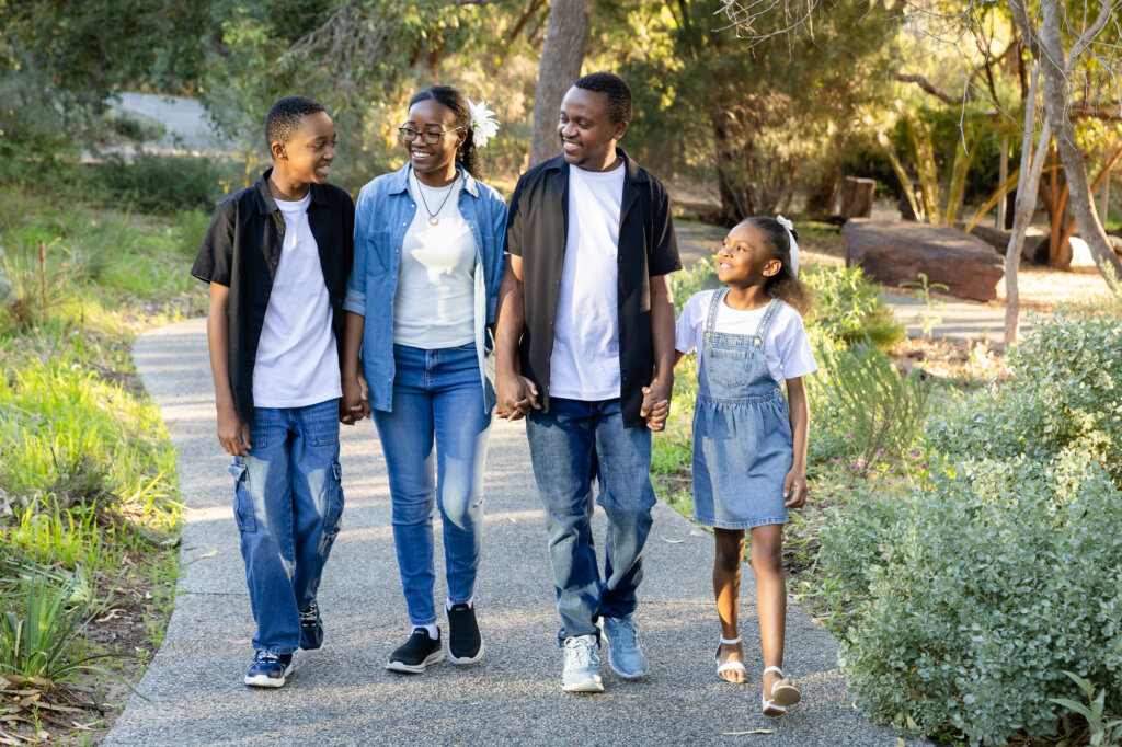 Family of four walking hand in hand through a Perth park at golden hour, family photography Perth