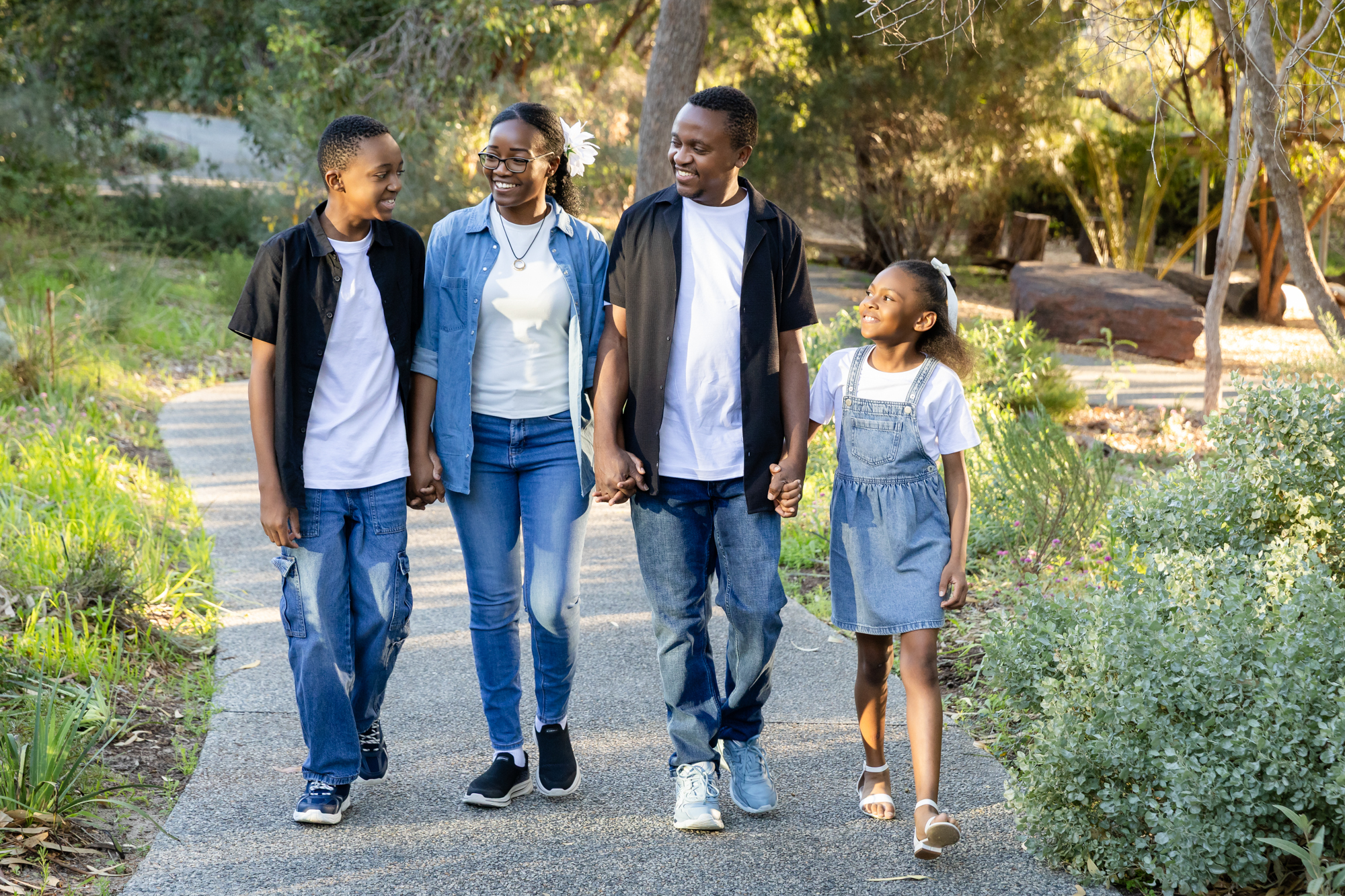 Family of four walking hand in hand through a Perth park at golden hour, family photography Perth
