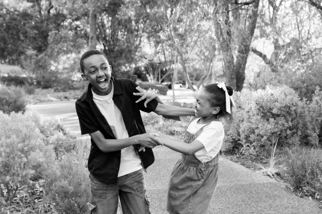 brother and sister playfully fighting and laughing outdoors, candid sibling portrait Perth family photos