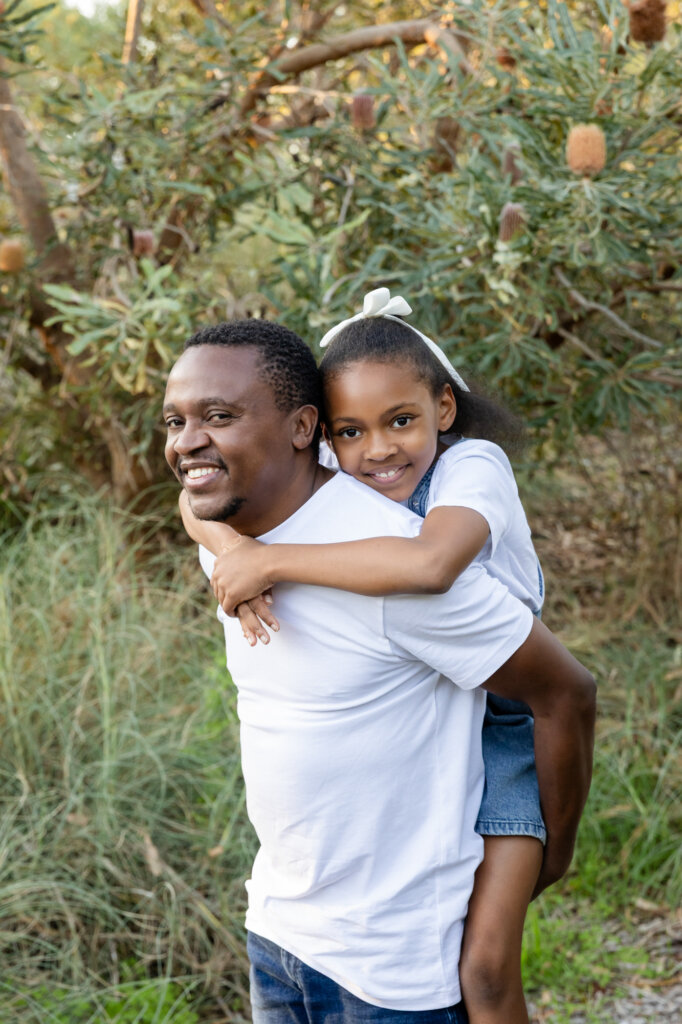 Dad giving his young daughter a piggyback ride outdoors, laughing together, Perth family photographer Erica Serena