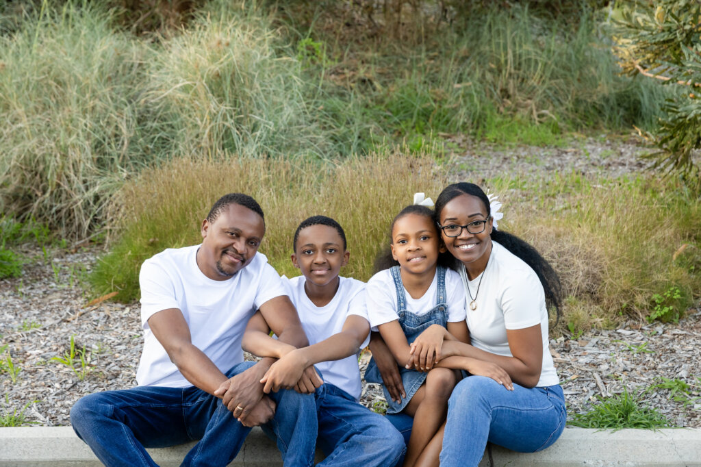 Family of four sitting together on a low wall outdoors, Perth family photography session