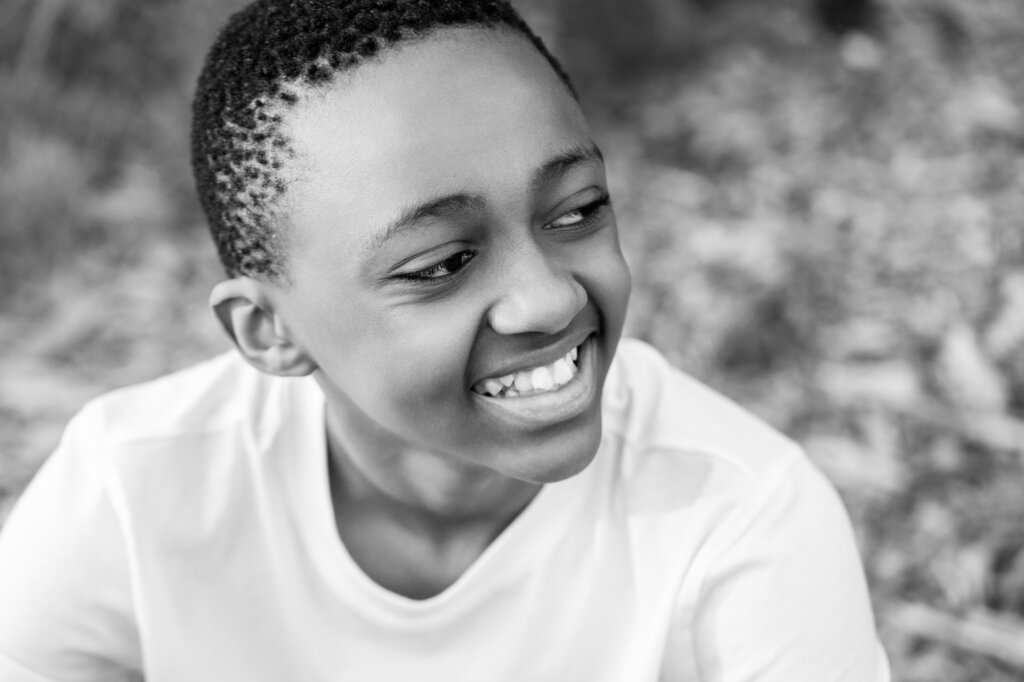 Black and white close up portrait of a teenage boy laughing outdoors, children's portrait photography Perth
