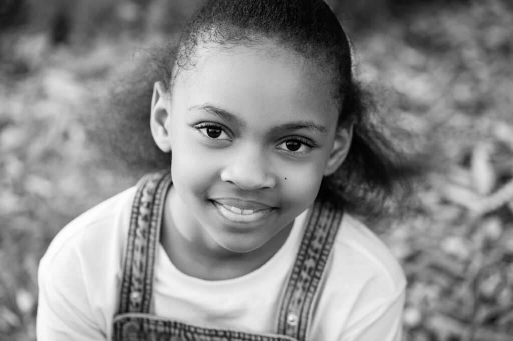Black and white close up portrait of a young girl smiling softly at camera, children's portrait photography Perth